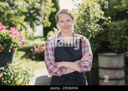 Ritratto di donna sicura con braccia incrociate in piedi in giardino Foto Stock