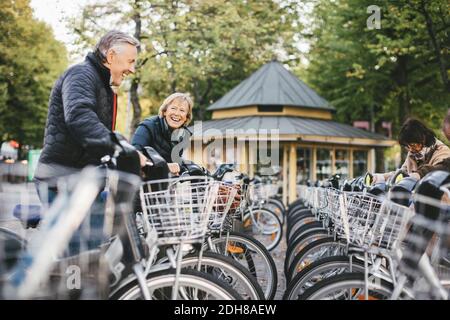 Persone anziane che prendono biciclette a noleggio nel parcheggio Foto Stock