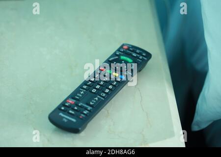 BALAI PANJANG, MALESIA - 06 dicembre 2020: Malacca, Malesia - 6 dicembre 2020. La televisione nera con telecomando sul tavolo da letto in marmo bianco. Th Foto Stock