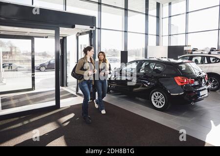 Gli amici parlano mentre entrano nello showroom dell'automobile Foto Stock