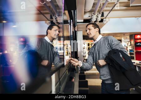 Giovane uomo che acquista per la televisione in negozio di elettronica Foto Stock