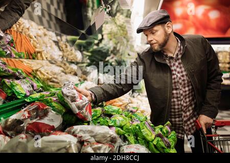 Uomo che acquista verdure fresche nel supermercato Foto Stock