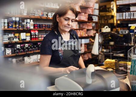 Calzolaio che usa il registratore di cassa nel negozio di riparazione Foto Stock