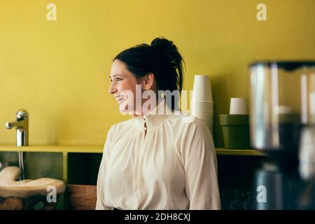 Una cameriera che si affaccia in una caffetteria Foto Stock