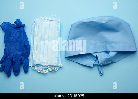 Cappuccio blu in tessuto, maschera medica monouso, paio di guanti su sfondo blu Foto Stock