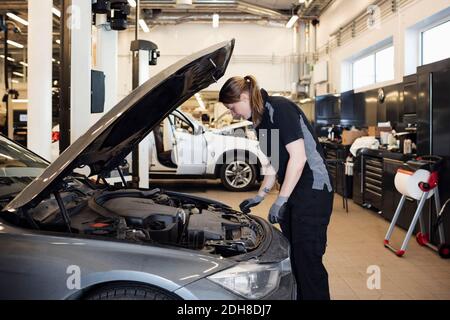 Vista laterale della donna che esamina l'auto in negozio Foto Stock