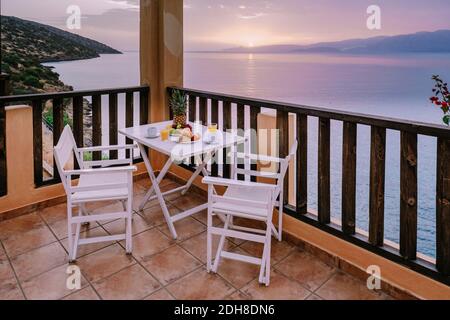 Tavolo e sedie con colazione all'alba al Meditarian Mare in Grecia Foto Stock