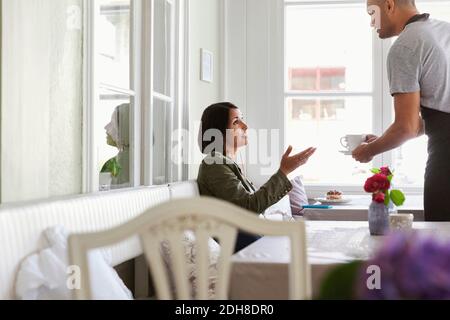 Una donna che parla con un uomo che serve caffè al bar Foto Stock