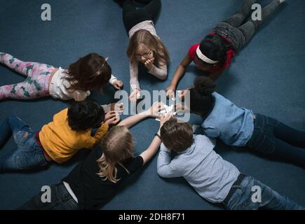 Direttamente sopra il colpo dei bambini che giocano mentre si sdraia sul pavimento a scuola Foto Stock