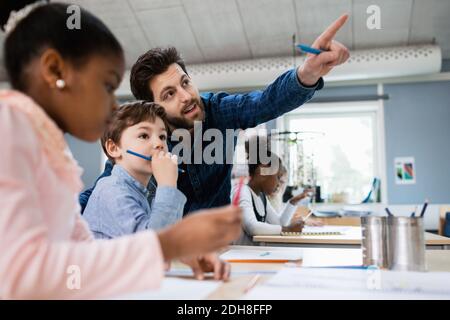 Insegnante che discute con il ragazzo mentre punta in classe a scuola Foto Stock