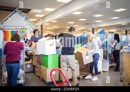 Volontari che organizzano scatole di cartone durante il lavoro in officina Foto Stock