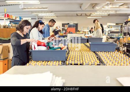 Volontari seri che controllano gli oggetti in casse sulla linea di produzione a. officina illuminata Foto Stock