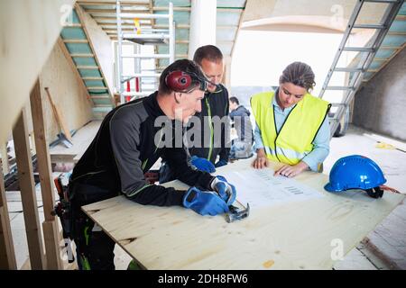 Vista ad alto angolo dei lavoratori edili che discutono di stampe blu in loco Foto Stock