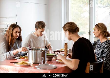 Famiglia avente pasto al tavolo da pranzo Foto Stock