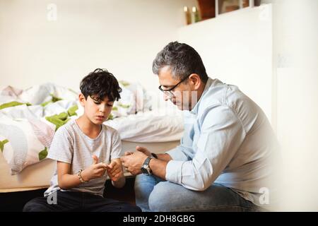 Padre e figlio suonano con bande di gomma a letto a. casa Foto Stock