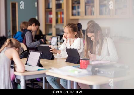 I bambini delle scuole superiori che usano il tablet digitale in classe Foto Stock