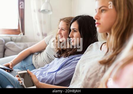 Le ragazze adolescenti guardano la TV mentre si rilassano sul divano a casa Foto Stock