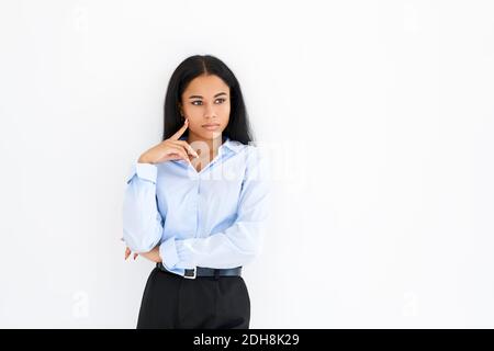 Donna d'affari afro-americana pensierosa che posa su sfondo bianco Foto Stock