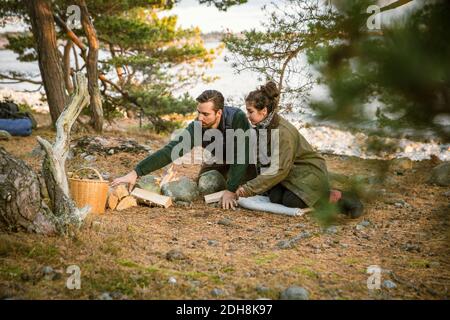 Coppia seduta dal fuoco pit al campeggio in foresta Foto Stock