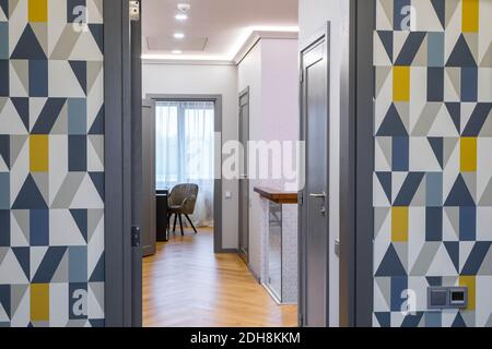 Interni moderni di appartamenti di lusso. Porta aperta da camera a sala. Carta da parati a mosaico. Pavimento in legno duro. Design domestico. Foto Stock