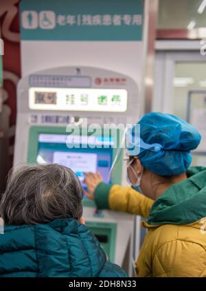 (201210) -- PECHINO, 10 dicembre 2020 (Xinhua) -- UN membro dello staff aiuta un anziano a prendere la ricevuta di appuntamento da una macchina dedicata agli anziani e ai disabili presso l'ospedale Xuanwu della Capital Medical University di Pechino, capitale della Cina, 10 dicembre 2020. La Cina ha lanciato una campagna triennale per aiutare gli anziani del paese ad attraversare il divario digitale e a godere dello sviluppo di tecnologie intelligenti. Il governo ha recentemente pubblicato un piano che specifica le misure per aiutare gli anziani a superare le barriere all'uso delle tecnologie intelligenti, mantenendo al contempo i servizi tradizionali per loro Foto Stock