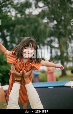 Ritratto di sorridere la figlia della sindrome giocando con il padre sopra trampolino durante l'estate Foto Stock