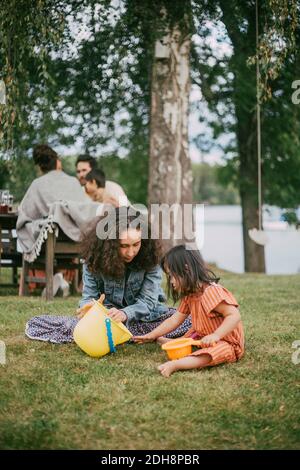 Teenager che gioca con la ragazza della sindrome giù mentre tiene il bucket dentro cortile Foto Stock