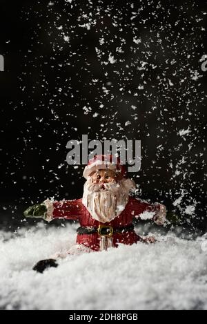 un babbo natale seduto sulla neve mentre nevica Foto Stock
