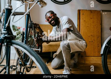 Ritratto di sorridente uomo che ripara la bicicletta in officina Foto Stock