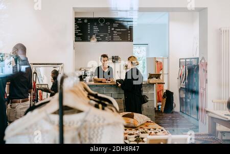 Il proprietario senior parla con una cliente femminile nel bar Foto Stock