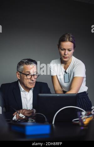 PROFESSIONISTA IT che assiste un collega maschile in ufficio creativo Foto Stock