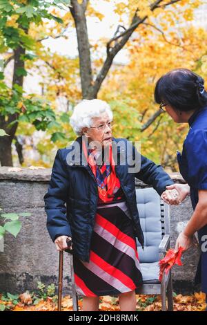 Custode che assiste donna anziana nel parco Foto Stock