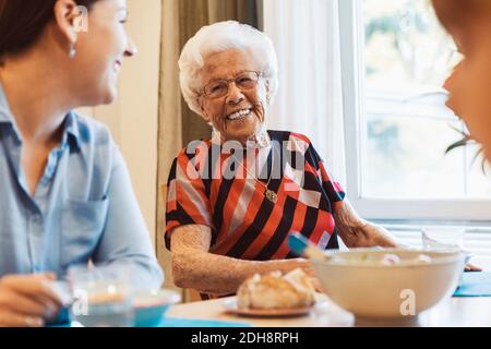 Donna anziana felice che parla con la figlia al tavolo da pranzo Foto Stock