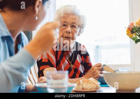 Donna anziana che parla con la figlia mentre ha cibo a casa Foto Stock