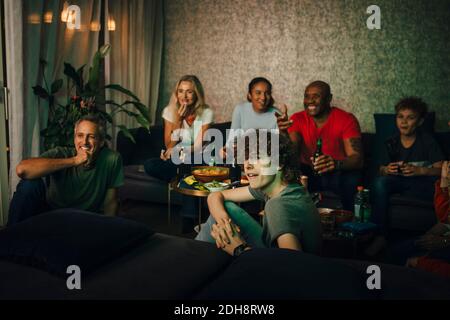 Sorridi amici e parenti che guardano gli sport di notte Foto Stock