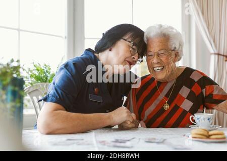 Felice custode e donna anziana seduto al tavolo Foto Stock