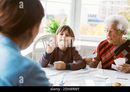 Felice ragazzo che gioca carte con madre e grande nonna a. casa Foto Stock