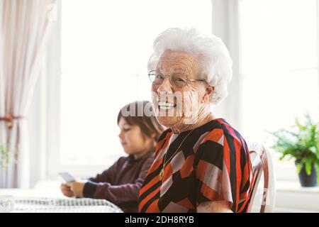 Ritratto di felice anziana seduta con grande nipote che gioca carte a casa Foto Stock