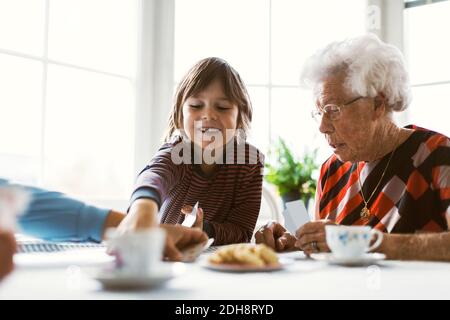 Felice ragazzo che gioca carte con la nonna grande e la madre a. tabella Foto Stock