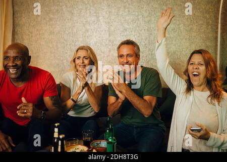 Donna allegra con mano sollevata godendo di partita con gli amici a. notte Foto Stock