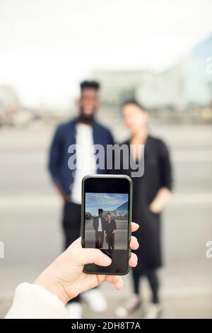 Immagine ritagliata di una donna che fotografa gli amici in città Foto Stock