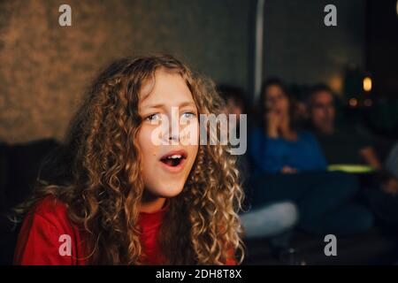 Sorridente ragazza con la famiglia che guarda gli sport in salotto a. notte Foto Stock
