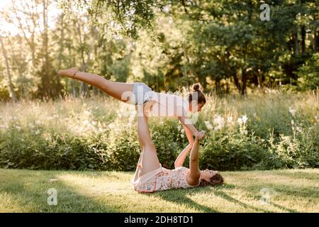 Sorridente sorella equilibrante ragazza sulla gamba in cortile Foto Stock