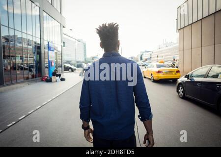 Vista posteriore dell'uomo che cammina in città Foto Stock