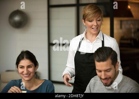 Uomini d'affari felici e donne che indossano il grembiule durante la degustazione Foto Stock