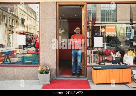 Il proprietario sorridente si trova all'ingresso del negozio Foto Stock