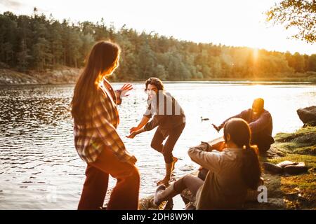 Amici di sesso maschile e femminile godendo di lago in foresta Foto Stock