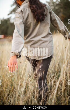 Vista posteriore della donna che cammina nel campo Foto Stock