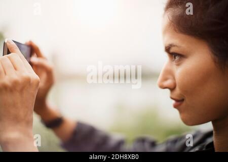 Vista laterale ravvicinata di una donna che fotografa attraverso uno smartphone Foto Stock