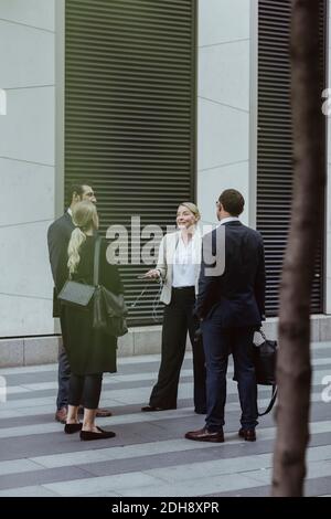 Sorridente imprenditore che parla con i colleghi mentre si trova in città Foto Stock